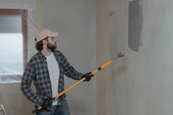 Painter rolling grey paint onto an interior wall in Birmingham
